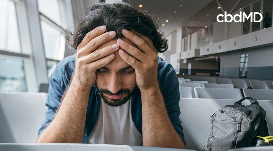 close-up of a man sitting at a gate at the airport with his head in his hands