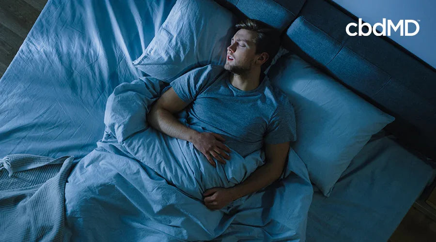 Man sleeping peacefully in bed at night, blue bedding, restful sleep concept