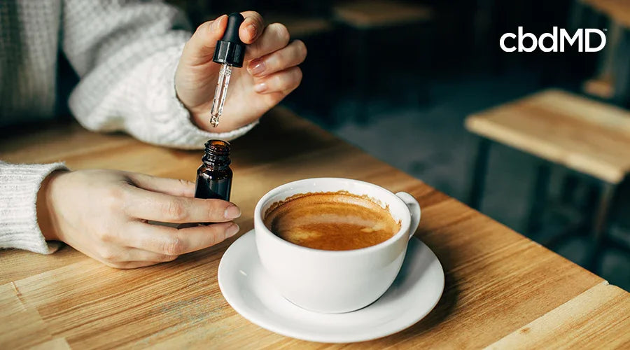 Person adding CBD oil to coffee in a cafe setting, wellness and health concept