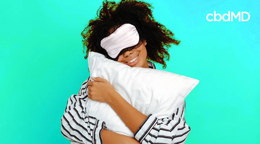 woman in pajamas and an eye cover hugging a pillow