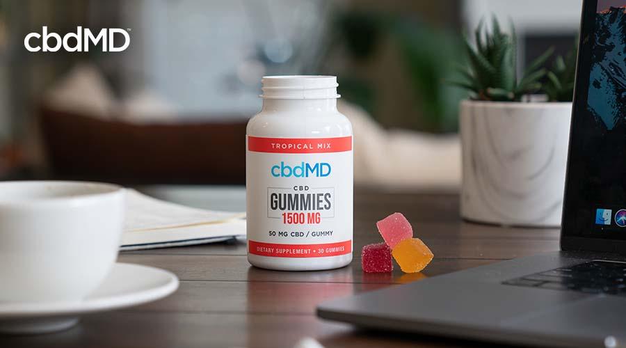 cbd gummies bottle on a counter next to a laptop