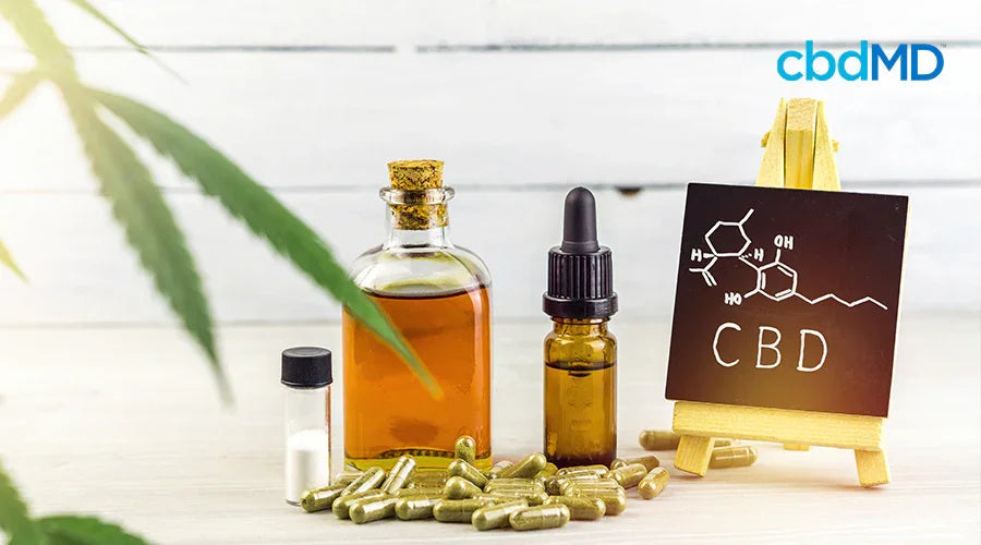 CBD oil, capsules, and dropper bottle with a chalkboard molecule diagram on a table