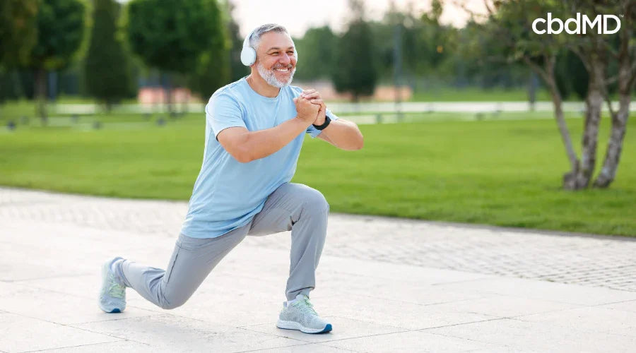 man doing lunges while wearing headphones in a park