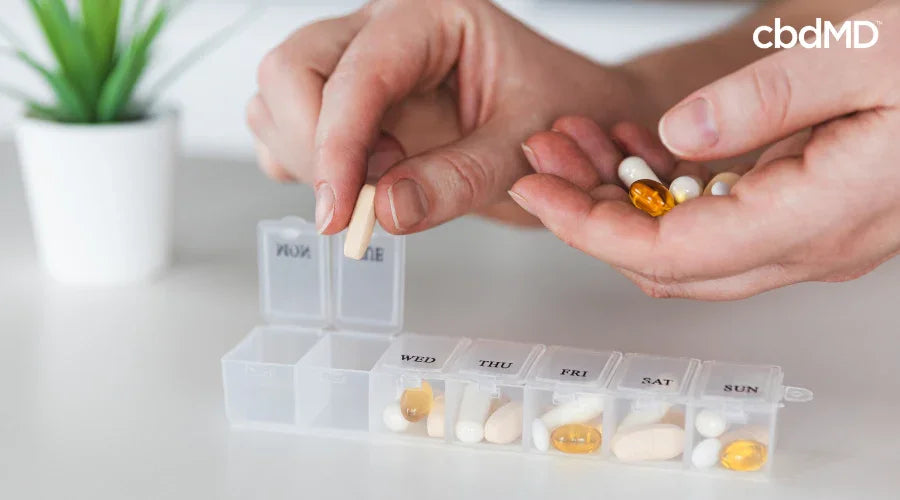 Person Adding CBD Capsules to Daily Pill Container