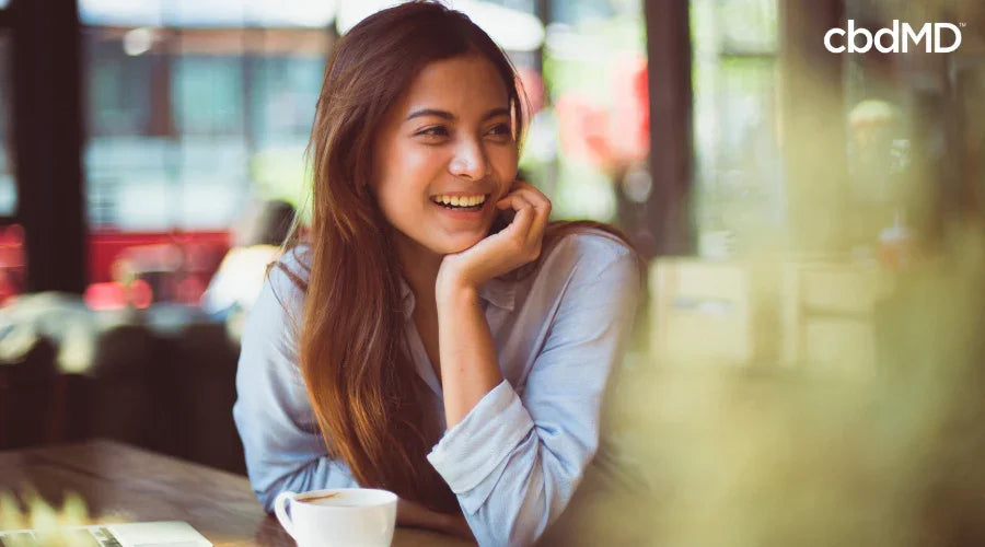 Smiling woman sitting at a table with coffee in a bright, relaxed indoor setting