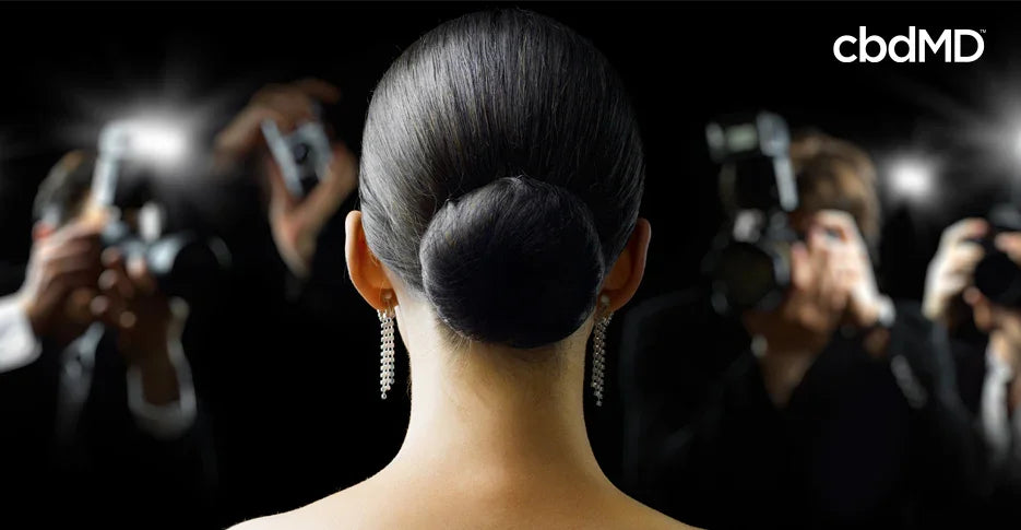 Woman with elegant updo and earrings facing paparazzi camera flashes at event