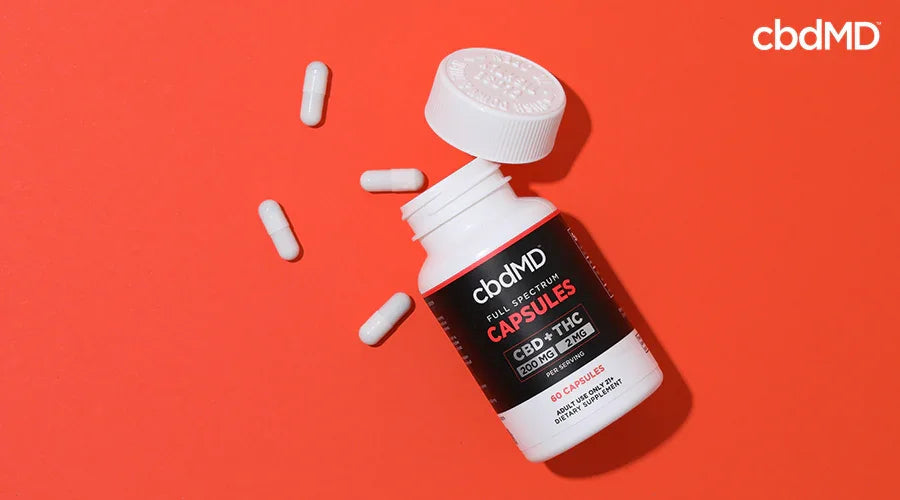 CBD capsules bottle with white capsules on red background, full spectrum formula