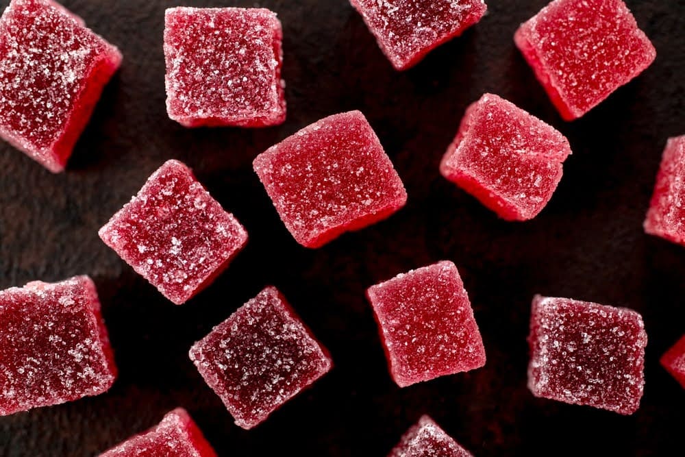 Red sugar-coated gummies arranged on a dark surface, close-up view