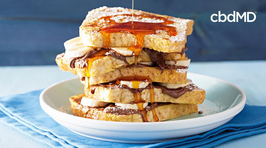 Stack of fluffy French toast slices with banana, chocolate spread, and syrup on a plate