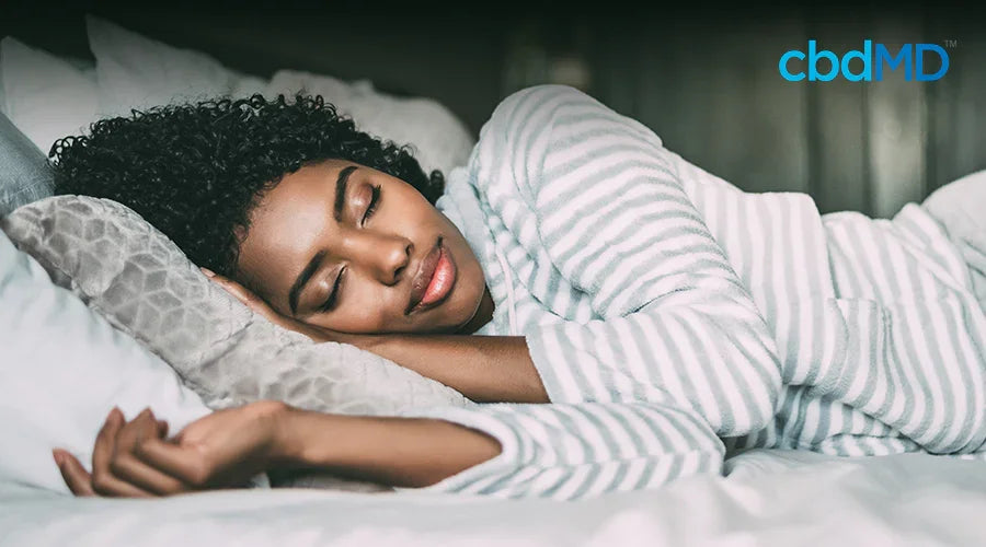 Woman peacefully sleeping on bed in striped pajamas, promoting restful sleep support
