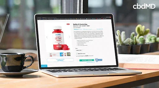 Laptop displaying Delta 9 THC gummies product page on desk with coffee cup and plants