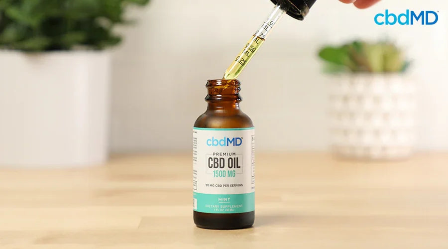 CBD oil tincture bottle with dropper, labeled 1500mg mint flavor, on wooden surface