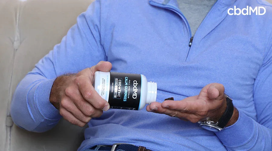 A man holding full spectrum calm gummies cbd plus thc mixed berry while pouring cbd gummies into his hand - cbdMD