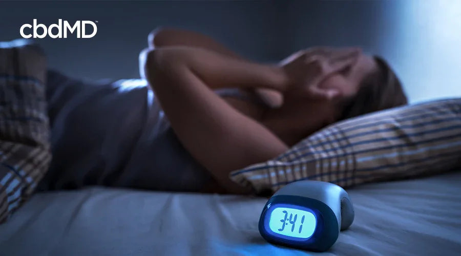 Person struggling to sleep at night with digital alarm clock showing 3:41 AM