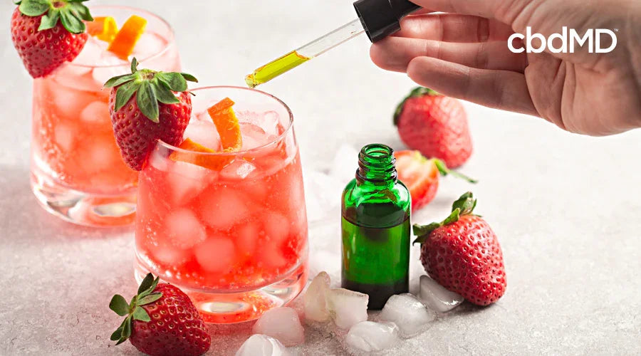 Iced strawberry drinks being infused with oil from a dropper, fresh strawberries nearby