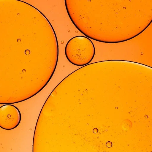 Close-up of orange oil droplets in liquid, abstract wellness and natural ingredient concept.