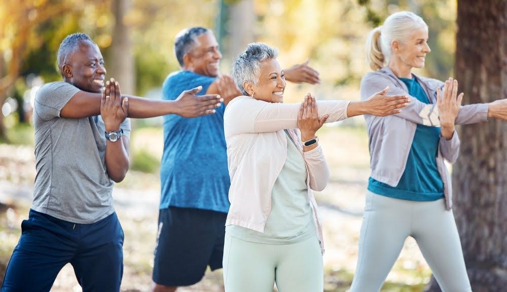 senior fitness group of two men and two women stretching in the park