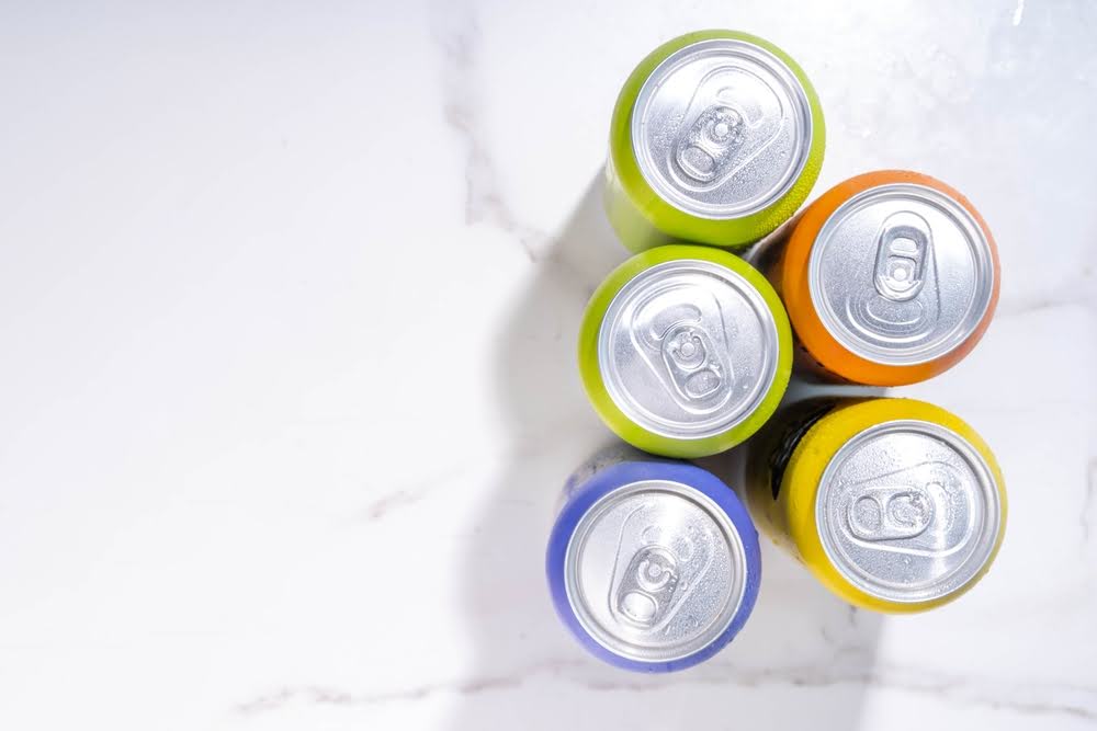 top-down shot of soda cans in a variety of colors on a marble patterned counter 