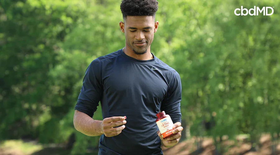 runner in a field holding a bottle in one hand and a delta 9 gummy in the other