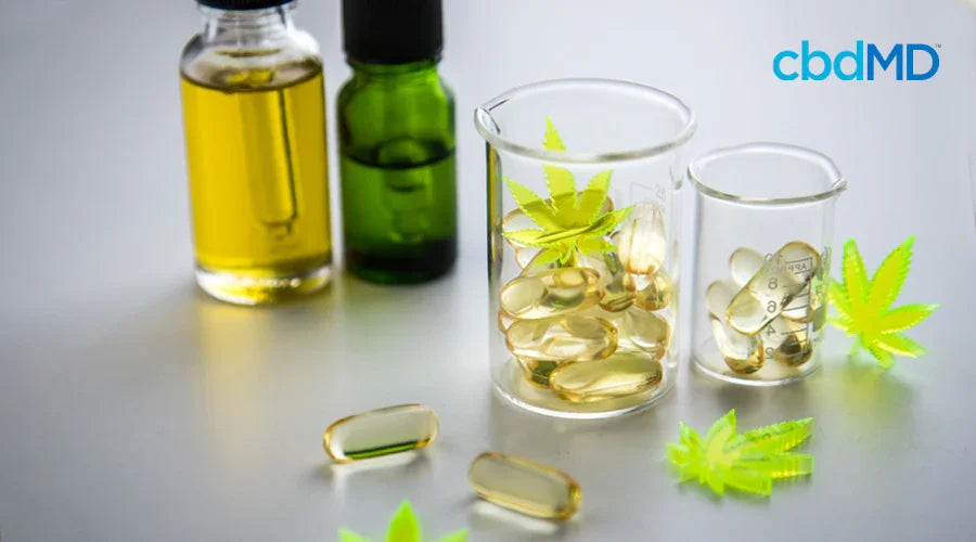CBD oil bottles, capsules, and hemp leaves on a white surface
