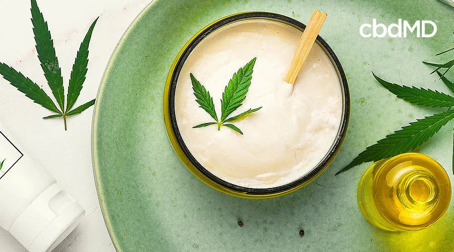 overhead view of cbd cream and oil on a green plate