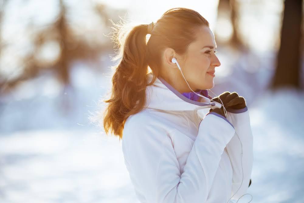 woman wearing headphones while standing in a snowy field